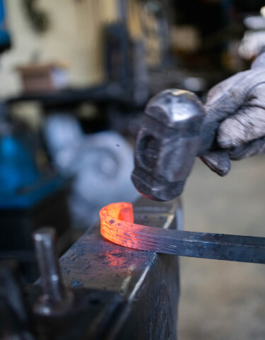 kintoart person is engaged in metalworking using a hammer to carefully mold a piece of metal