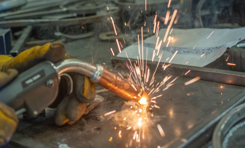 kintoart person welding metal creating bright sparks that illuminate the workspace