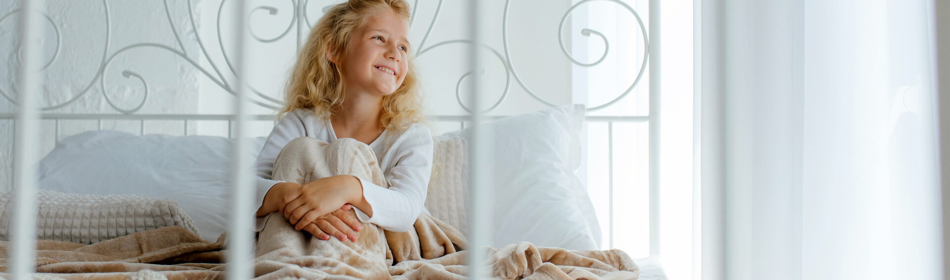 kintoart young girl sits on a bed wrapped in a cozy blanket with a serene expression on her face